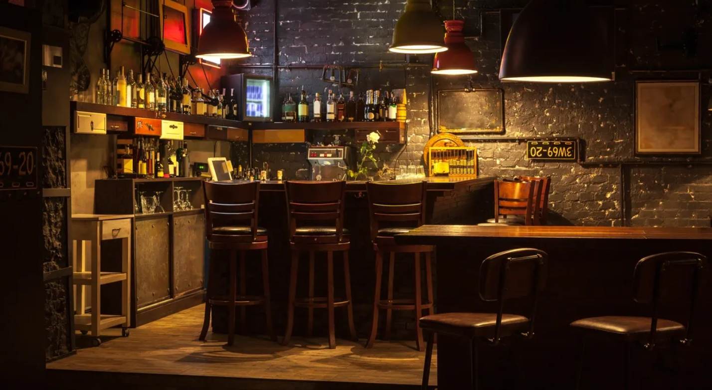 A bar with several stools and tables in it.