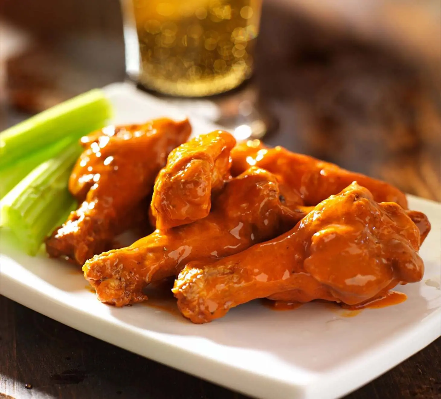 A plate of chicken wings with celery and beer.