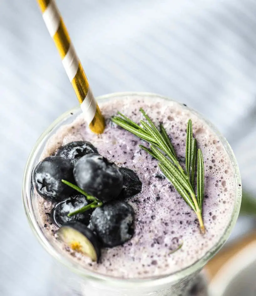 A close up of a smoothie with blueberries and rosemary