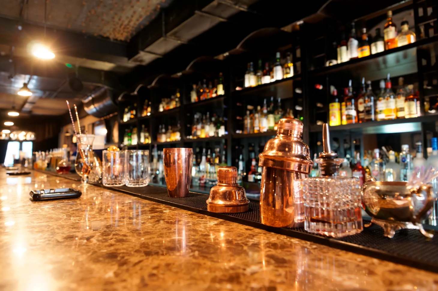 A bar with many bottles of alcohol on the counter