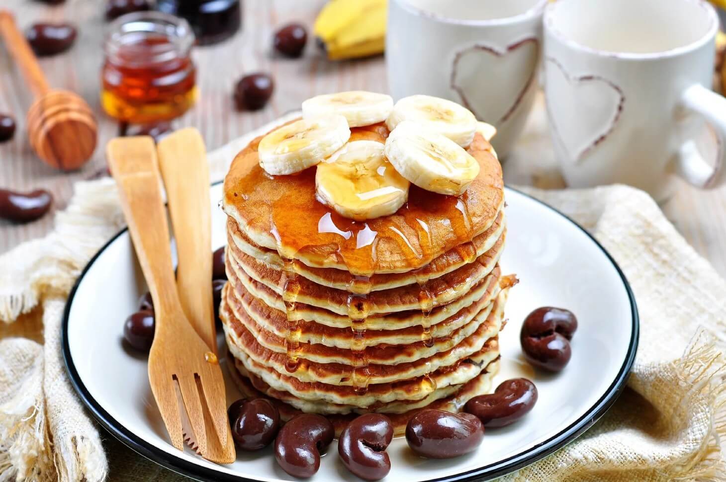 A plate of pancakes with bananas and maple syrup.