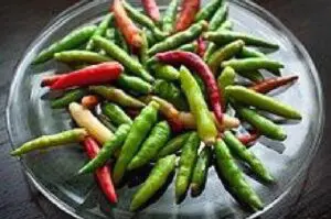 A vibrant display of chili peppers in a glass bowl on a table, showcasing the rich and fiery culinary traditions.