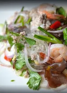 Vietnamese noodle salad with shrimp and vegetables, showcasing culinary traditions, on a white plate.