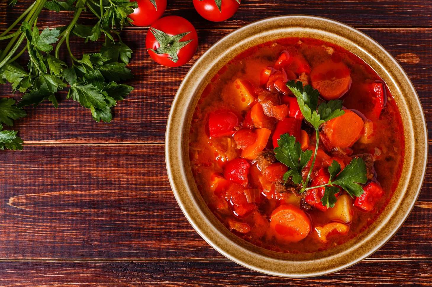 A bowl of stew with tomatoes and parsley.