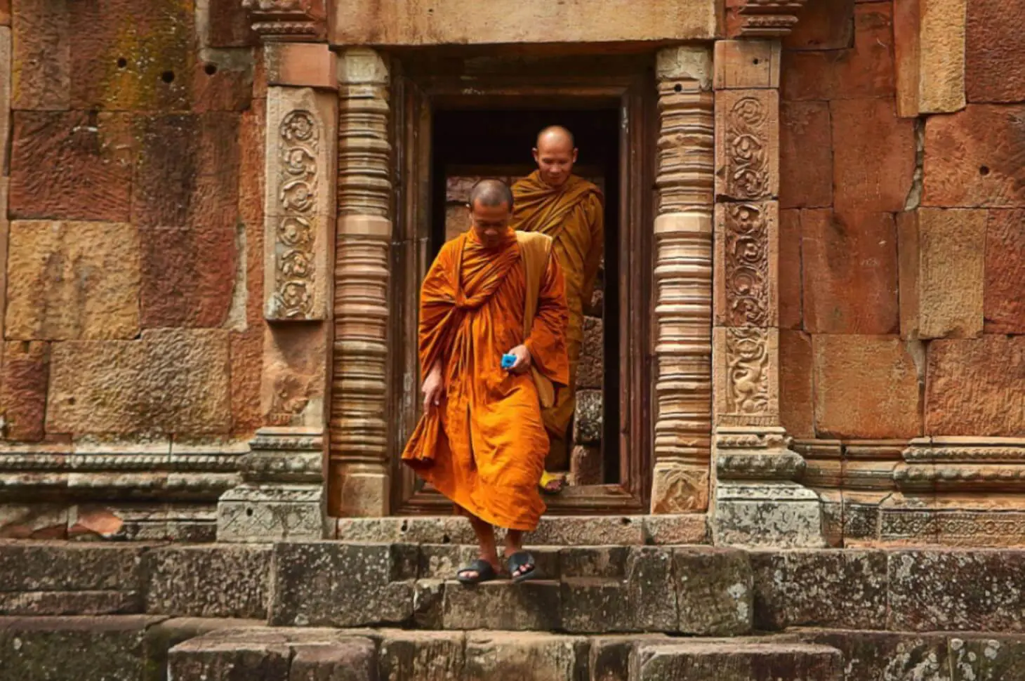 Two monks are walking down the steps of a temple.