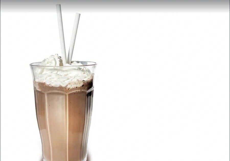 A glass of chocolate milk with whipped cream.